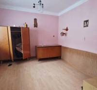 Ein Zimmer in einem Einfamilienhaus mit rosa Wänden, einem Kleiderschrank und einem Boden in Holzoptik.