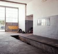 Produktionsräume mit großen Fenstern, einem Garagentor und einem Boden mit Holzdekor.