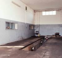 Produktionsräume mit Ausstattung, Betonboden, graue Wände, Wartungsbereich für Fahrzeuge.