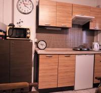 Küche mit Holzdekor, Mikrowelle, zwei Uhren und Geräten auf der Arbeitsplatte.