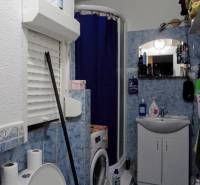 Badezimmer in einer 3-Zimmer-Wohnung mit blauen Fliesen, Waschmaschine und Duschkabine.