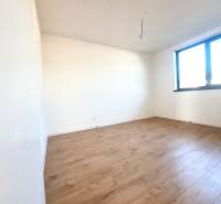 Ein leerer Raum mit Holzboden und einem großen Fenster in einem Einfamilienhaus.