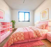 Ein rosa Schlafzimmer in einem Einfamilienhaus mit Holzboden, Kleiderschrank und Pflanze.