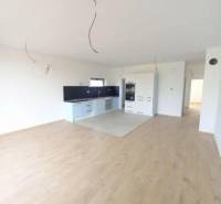 Küche mit weißen Schränken, dunkler Arbeitsplatte und Bodenbelag in Holzoptik.