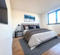 Schlafzimmer in einem Einfamilienhaus mit Bett, Bild, Fernseher und Boden in Holzoptik.