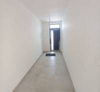 Ein schmaler weißer Flur mit Fliesen und Eingangstüren in einem Einfamilienhaus.