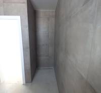 Ein Badezimmer in einem Einfamilienhaus mit großformatigen Fliesen und einer Duschzone ohne Duschwanne.