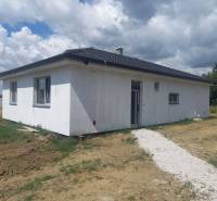 Ein Einfamilienhaus in Galanta mit weißer Fassade auf einem grasbewachsenen Grundstück unter einem bewölkten Himmel.