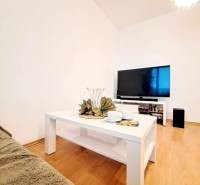 Wohnzimmer in einer 2-Zimmer-Wohnung mit Holzboden und weißem Tisch.