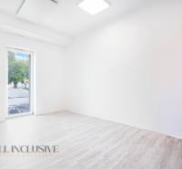 Ein leeres Büro mit einem Boden in Holzoptik und einem großen Fenster.