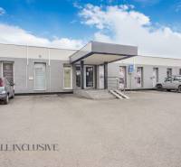 Einstöckiges Gebäude mit Geschäftsräumen in der Vajanského-Straße, Parkplatz und Autos vor dem Eingang.