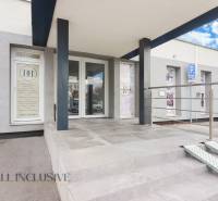 Eingang zu den Geschäftsräumen in der Vajanského-Straße, mit barrierefreiem Zugang und einem Parkplatz.