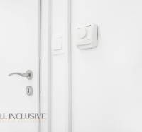 Weiße Wand mit Thermostat und Türklinke im Büro.