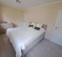 Schlafzimmer in einem Einfamilienhaus mit Bett, Kommode und Boden in Holzoptik.