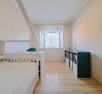 Ein Zimmer eines Einfamilienhauses mit einem Bett, einem Bücherregal und einem Boden mit Holzdekor.