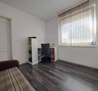 Izba v rodinnom dome s podlahou s dreveným dekorom, stolom, stoličkou a pohovkou.