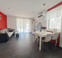 Wohnzimmer in einem Einfamilienhaus mit roter Wand, grauen Fliesen und weißen Möbeln.