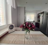 Eine Küche in einem Einfamilienhaus mit einer Vase voller Tulpen auf dem Tisch und weißen Vorhängen.