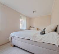 Helles Schlafzimmer in einem Einfamilienhaus mit bequemem Bett und Boden in Holzoptik.