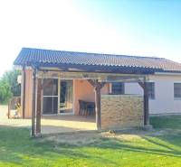 Ein Einfamilienhaus in Čierny Brod mit Terrasse, Garten und Pergola, umgeben von einem grünen Rasen.