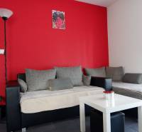 Innenraum eines Einfamilienhauses mit grauen Sofas, roter Wand und weißem Tisch.
