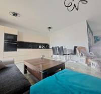 Wohnzimmer in einem Einfamilienhaus mit offener Küche und Esstisch. Boden mit Holzdekor.