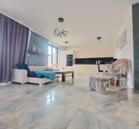 Wohnzimmer mit großen Fenstern und hellen Fliesen in einem Einfamilienhaus.