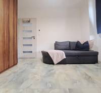 Ein Zimmer in einem Einfamilienhaus mit einem Sofa, einem Schrank, einer Tür und einem Boden mit Marmordekor.