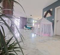 Innenraum eines Einfamilienhauses mit einem Zelt für Kinder auf einem glänzenden Boden und Pflanzen.