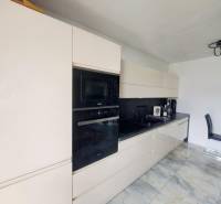 Küche in einem Einfamilienhaus mit glänzender Küchenzeile und eingebauten Geräten, Boden mit Marmormuster.