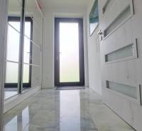 Innenraum eines Einfamilienhauses mit glänzendem Keramikboden und Glastüren.