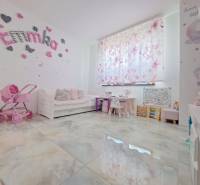 Kinderzimmer in einem Einfamilienhaus mit Dekorationen, Kinderwagen und Schreibtischen. Der Boden hat ein Holzdekor.