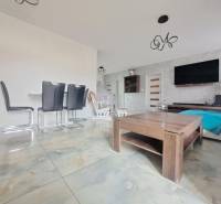 Innenraum eines Einfamilienhauses mit hellen Fliesen, modernen Möbeln und einer Wand mit Fernseher.