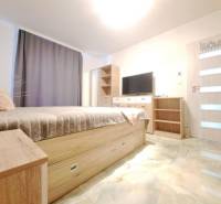 Schlafzimmer im Einfamilienhaus mit Bett, Kleiderschrank, Fernseher und Boden mit Holzdekor.