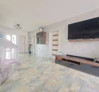 Wohnzimmer in einem Einfamilienhaus mit einem Fernseher an der Wand, einem Zelt und einem Keramikboden.