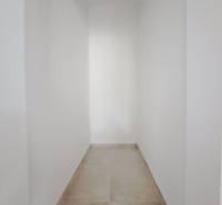 Ein enger Flur in einem Einfamilienhaus mit weißen Wänden und hellem Boden.