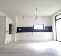 Küche in einem Einfamilienhaus mit Holzboden, weißen Schränken und eingebauten Geräten.