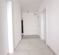 Ein heller Flur in einem Einfamilienhaus mit weißen Wänden und hellem Fliesenboden.