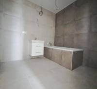 Badezimmer in einem Einfamilienhaus mit Fliesen und Badewanne auf neutralen Fliesen.