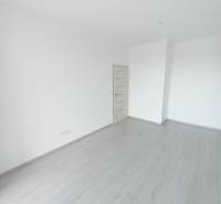 Ein Zimmer in einer 2-Zimmer-Wohnung mit weißen Wänden und einem Boden in Holzoptik.