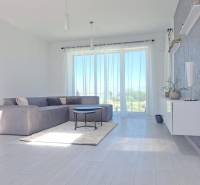 Helles Wohnzimmer in einer Zweizimmerwohnung mit großen Fenstern und Holzboden.