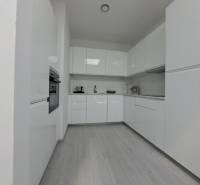 Moderne Küche mit weißen Schränken und Holzboden in einer Zweizimmerwohnung.