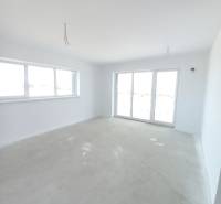 Ein geräumiges Zimmer in einer 2-Zimmer-Wohnung mit hellen Wänden und großen Fenstern.