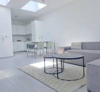 Helles Wohnzimmer mit Küche, Sofa und Holzboden in einer 2-Zimmer-Wohnung.