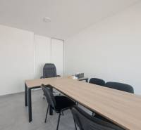Bürotische und schwarze Stühle in Geschäftsräumen mit minimalistischem Interieur.
