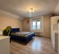 Schlafzimmer in einem Einfamilienhaus mit Holzdekorboden, Bett und Schreibtisch.