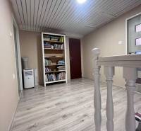 Flur mit Holzboden, Bücherregal und hellem Holzgeländer in einem Einfamilienhaus.