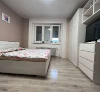 Helles Schlafzimmer in einem Einfamilienhaus mit Bett, Kleiderschrank und Boden in Holzoptik.