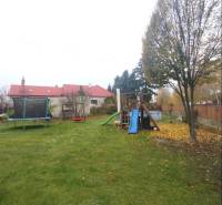 Ein Einfamilienhaus in Dunajská Streda mit einem Rasen im Garten, einem Trampolin und einem Kinderspielplatz.