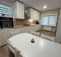 Küche in einem Einfamilienhaus mit weißen Möbeln und einem Boden in Holzoptik.